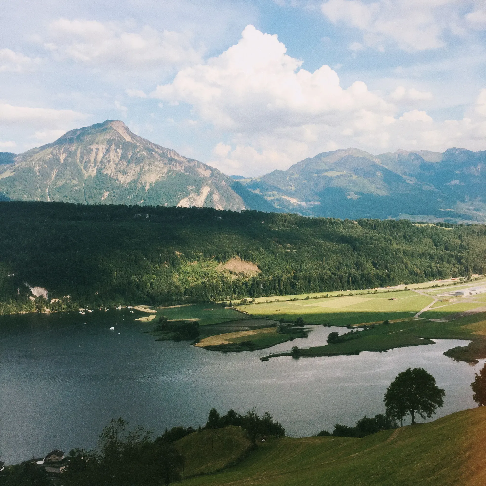 Train suisse près d’un lac avec montagnes et lumière claire